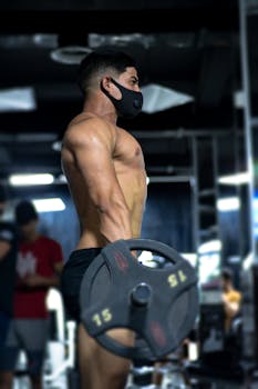 Athlete wearing face mask lifting weights indoors, showcasing strength and focus.