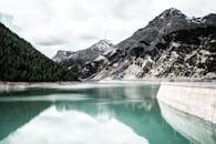 意大利利维尼奥的壮丽景色中，宁静的湖泊倒映着白雪皑皑的山脉