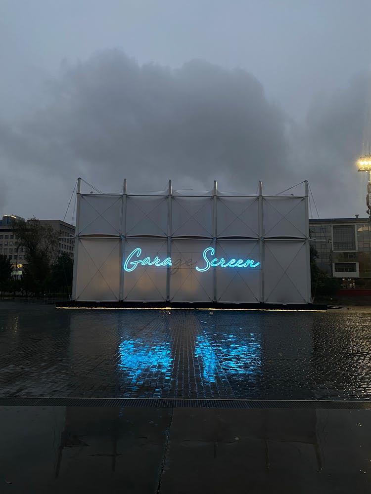 A Blue Neon Signage With Broken Lights On A Wet Floor