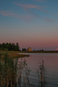 Beautiful sunset over a serene lake and countryside house in Estonia.