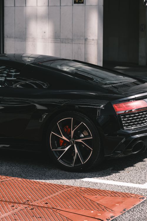 Free Black sports car parked in city street, showcasing modern design and luxury automotive style. Stock Photo