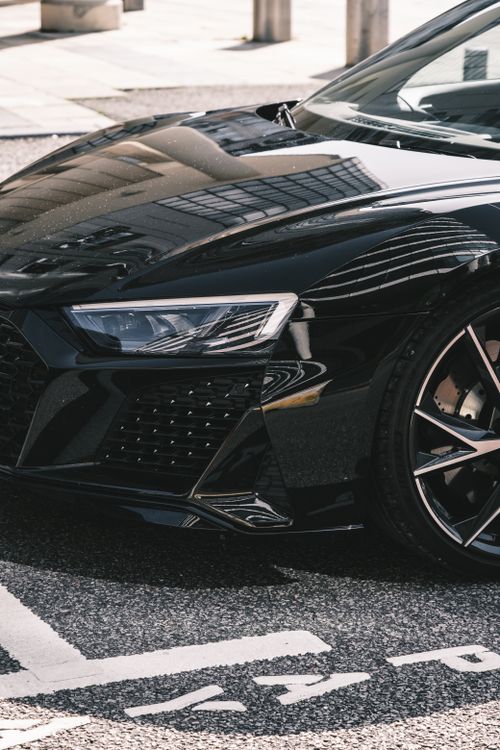 Free Close-up of a parked black sports car reflecting tall buildings in a city environment. Stock Photo