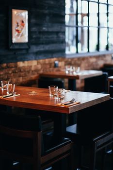 Warm and inviting restaurant interior with wooden tables and elegant glassware, perfect for dining.
