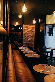 Intimate bar setting with leather seats, warm lighting, and wooden tables, perfect for dining and relaxation.