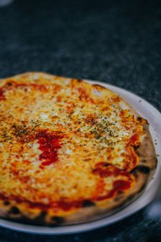 Delicious Margherita pizza with melted cheese and herbs on a white plate, perfect for food lovers.