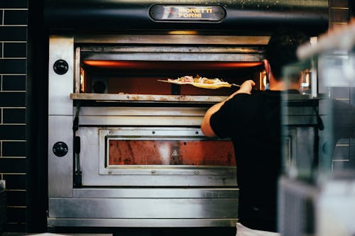 Person Putting Pizza Inside the Oven