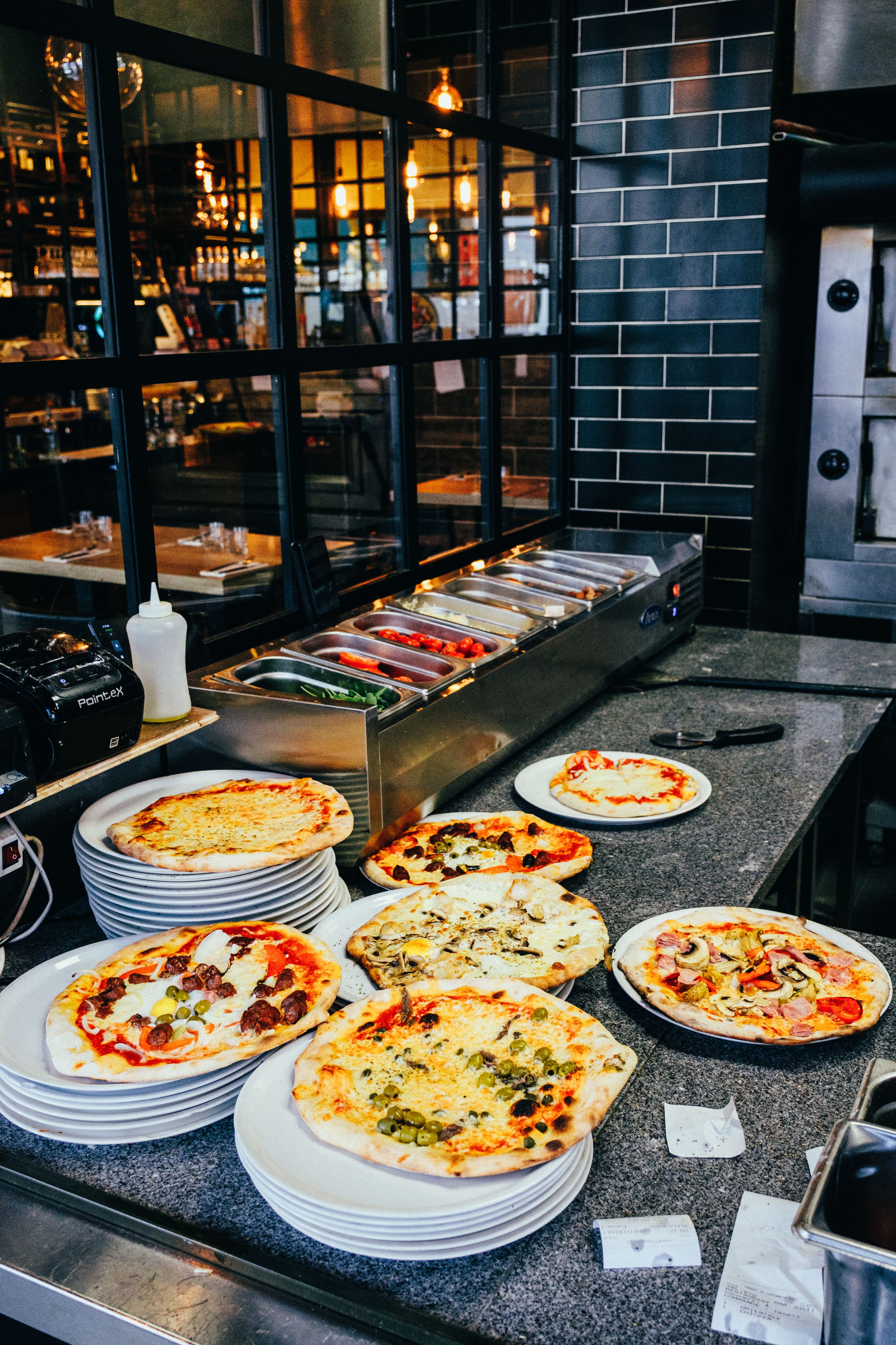A variety of freshly baked pizzas displayed on plates in a rustic restaurant setting, perfect for food lovers.