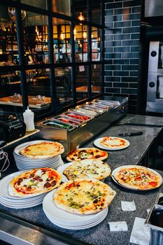 A variety of freshly baked pizzas displayed on plates in a rustic restaurant setting, perfect for food lovers.