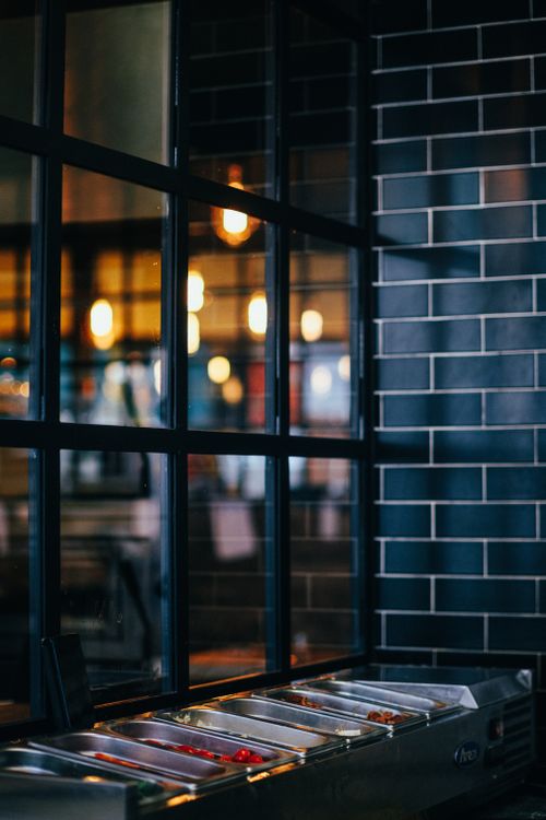 Free Stylish restaurant interior featuring a glass partition and modern lighting that sets a warm ambiance. Stock Photo
