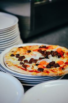 Tasty beef pizza served on stacked plates, showcasing a savory meal indoors.