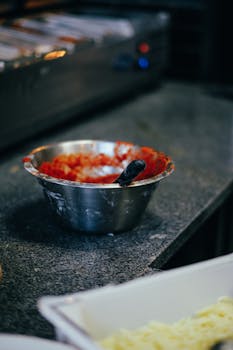Close-up of tomato sauce in stainless steel bowl on kitchen counter, creating a rustic culinary vibe.