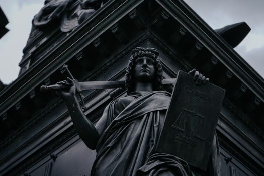 Striking statue of Lady Justice holding sword and scales in Dresden, Germany.