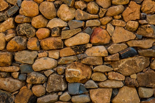 Detailed view of a rustic stone wall pattern, showcasing natural earthy tones and texture.
