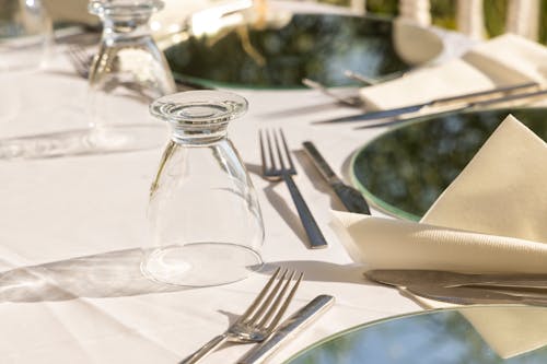 Clear Glass Bottle Beside Silver Fork and Knife on White Table