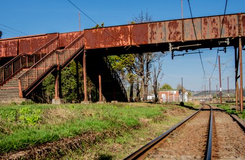 Free An old rusty railway footbridge over tracks surrounded by nature. Stock Photo