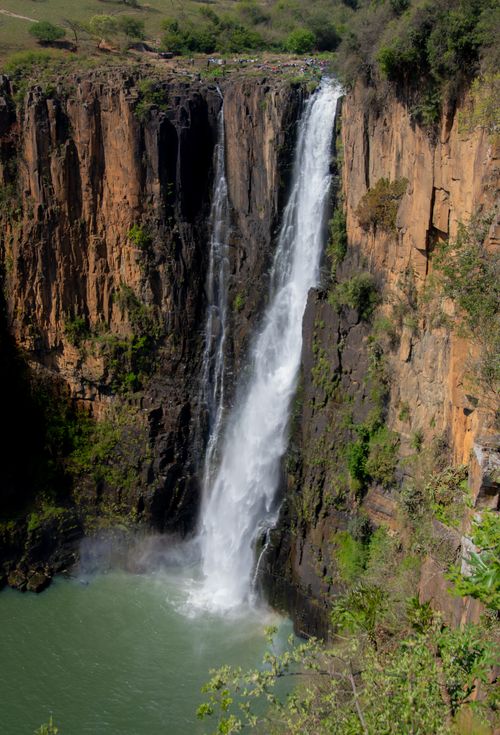 Free Stunning tall waterfall cascading down rugged cliffs into a serene pool. Stock Photo