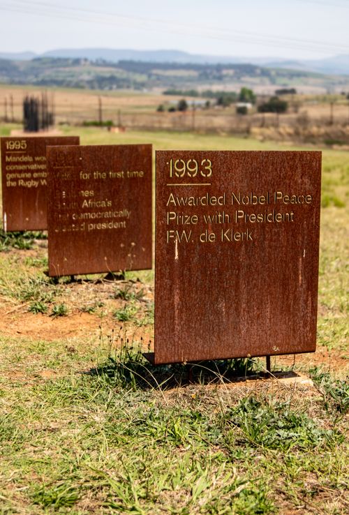 Free Rusty sign highlighting historical event set in a grassy countryside field. Stock Photo