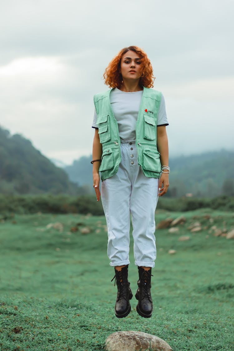 Woman In Green Vest Jumping On Rock