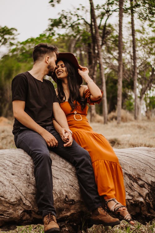 A Man in Black Shirt and Woman in Orange Dress Kissing