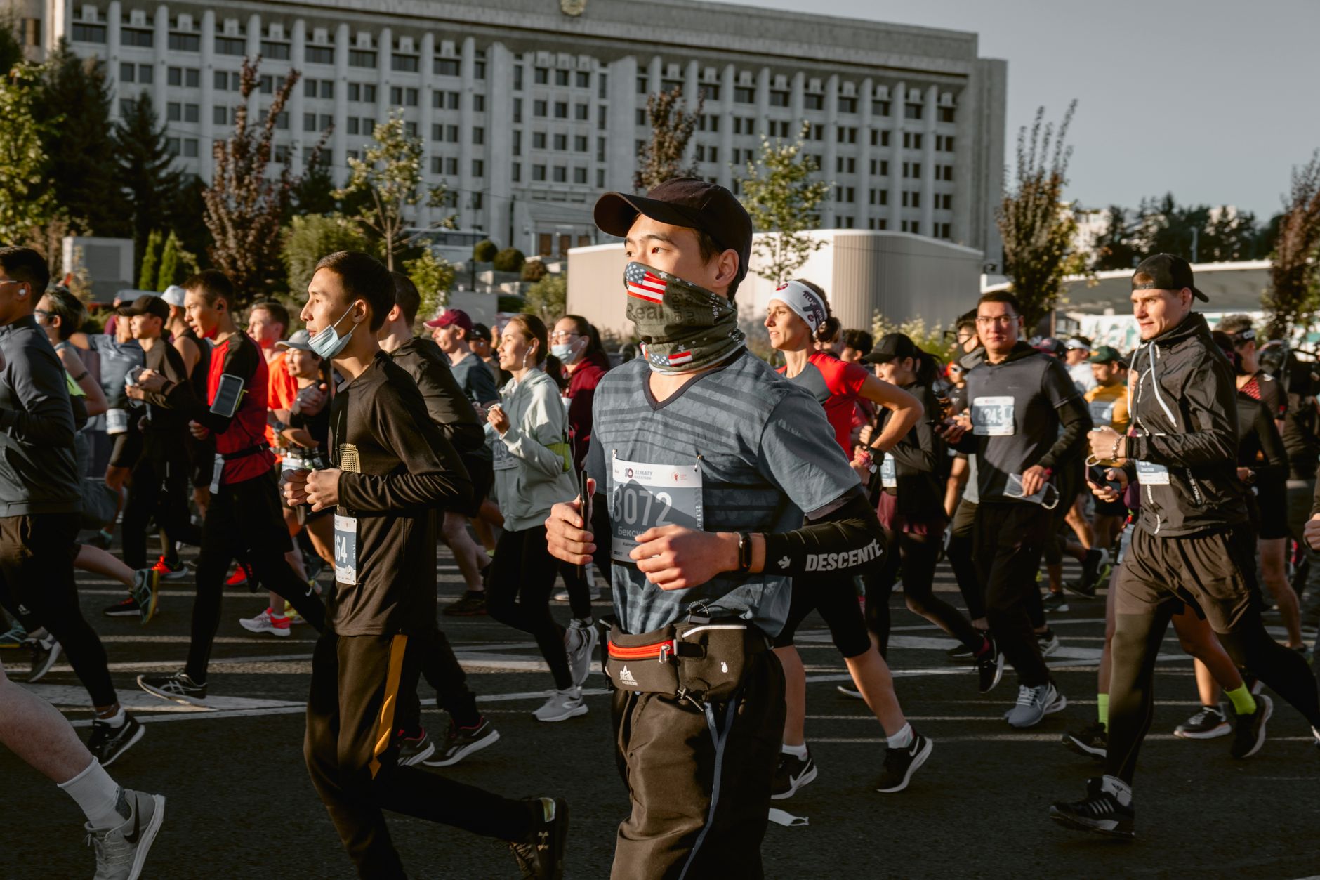 A vibrant marathon in an urban setting with runners wearing face masks and activewear.