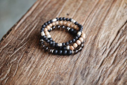 Close-Up Photo of Bracelets with Beads on Top of a Wooden Surface