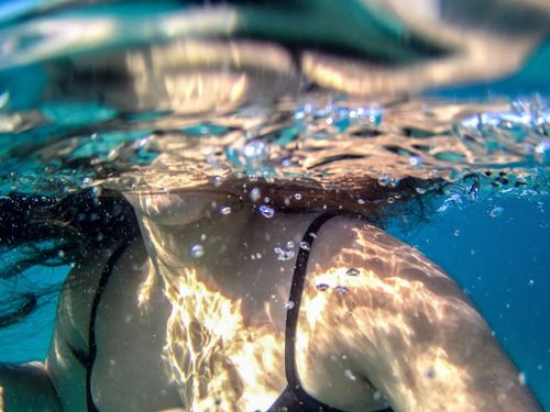 Free Underwater shot of a woman swimming, creating bubbles in Akrata, Greece. Stock Photo