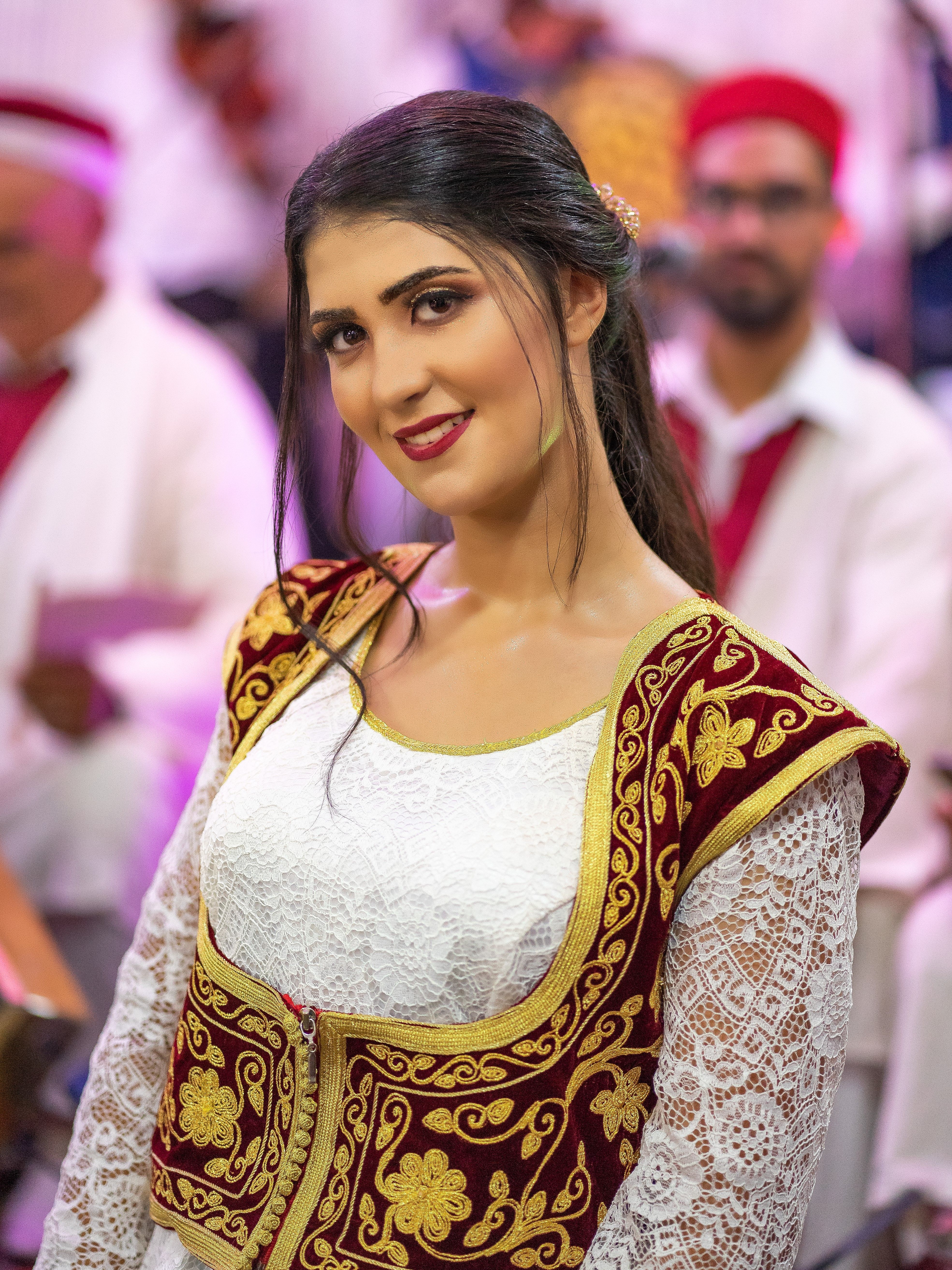 A smiling woman in traditional Tunisian attire at a cultural gathering in Nabeul.
