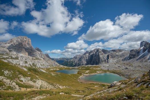 Breathtaking landscape of Dolomite mountains with clear alpine lakes under a bright blue sky.