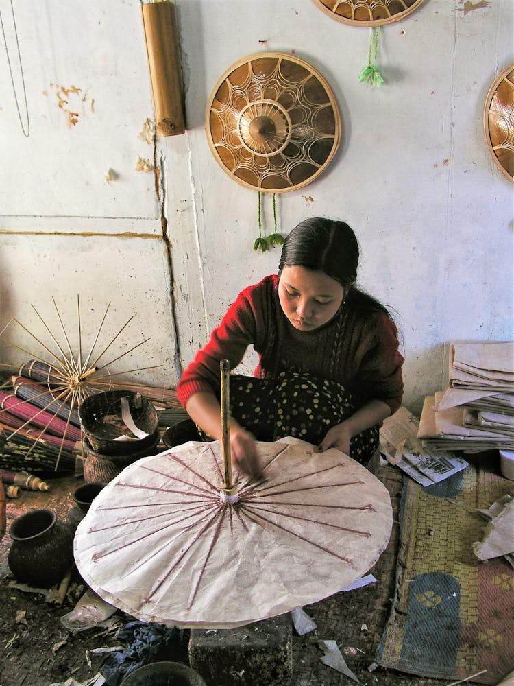 Woman In Red Long Sleeves Sewing A Parasol