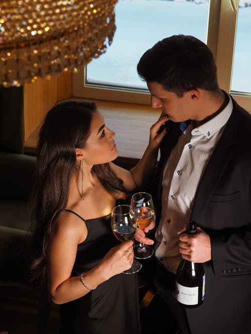 A Couple Looking at Each Other while Holding a Glass of Wine