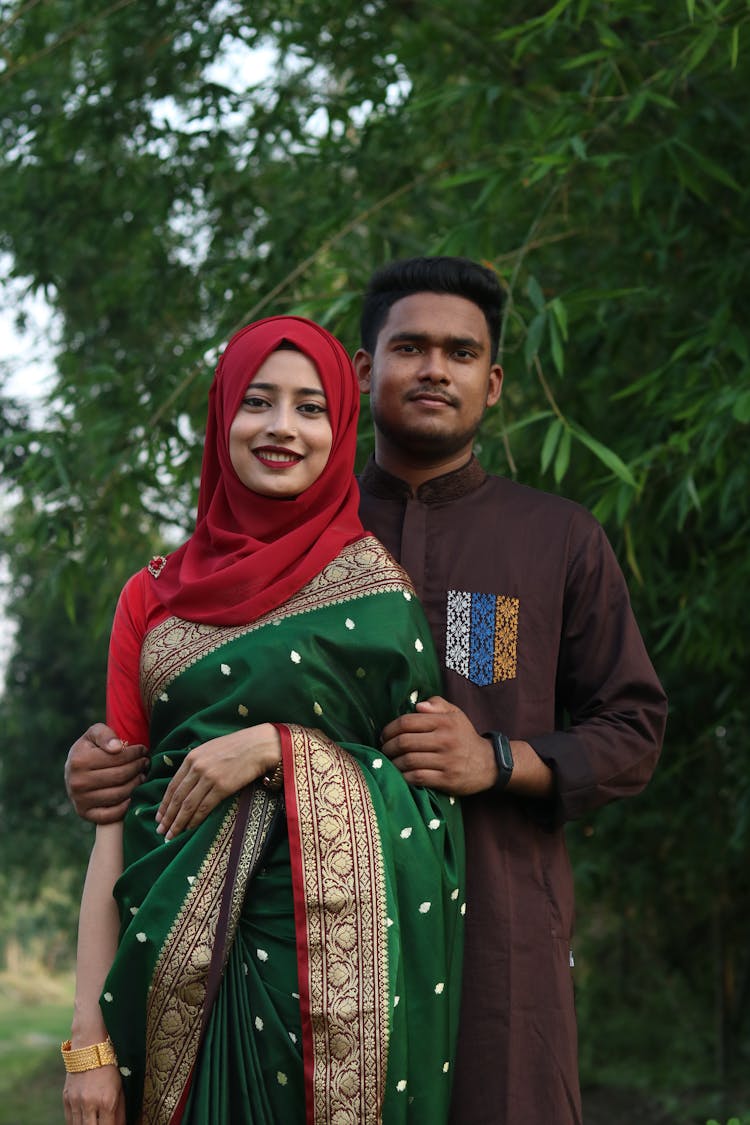 A Woman In Red Hijab Standing Beside Her Partner In Brown Long Sleeves