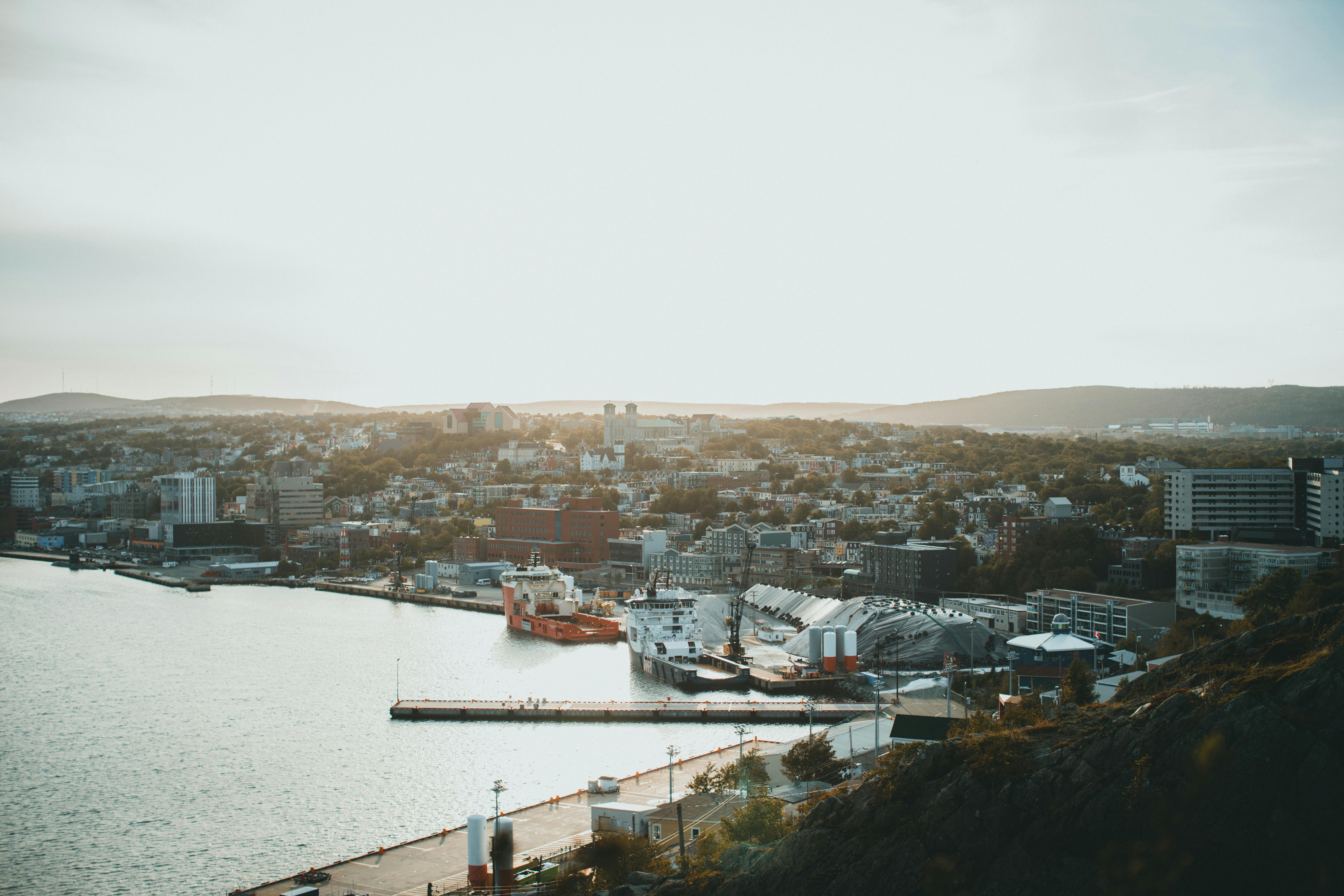A breathtaking aerial view of a coastal cityscape at sunrise, featuring urban architecture and serene waters.
