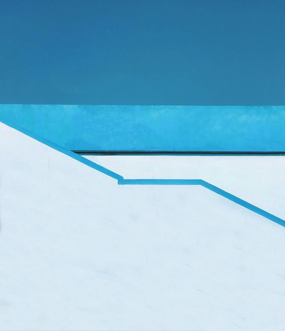 Abstract minimalist architecture with blue sky and white geometric shapes.