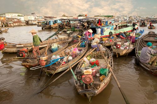 Free Vibrant floating market in Vietnam with locals trading goods on boats during daytime. Stock Photo