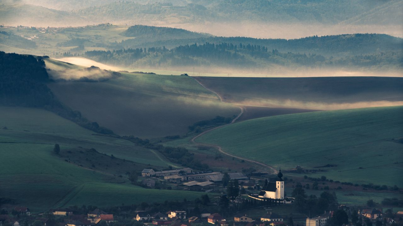 a captivating aerial view of a mist covered village nestled in rolling