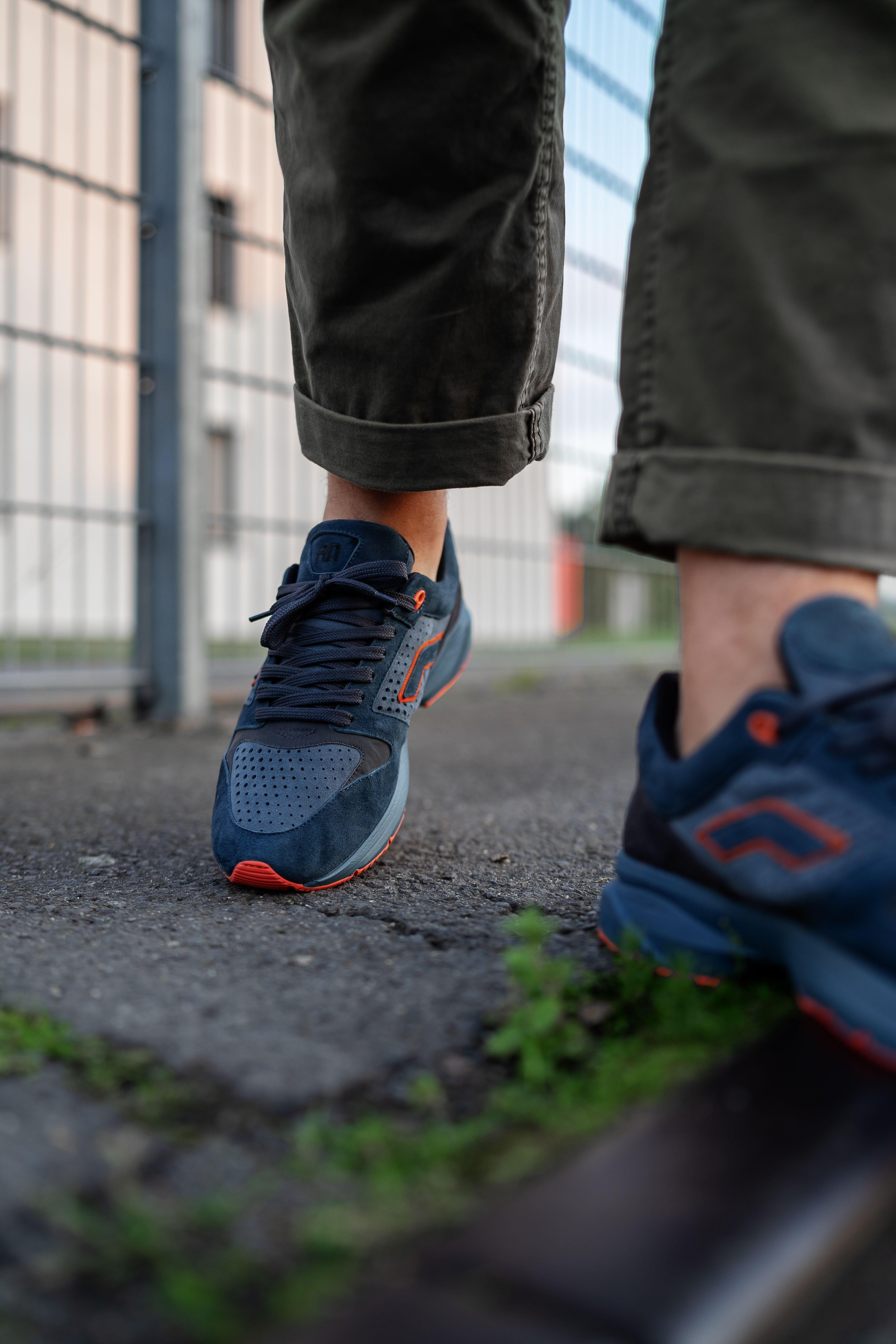 A person walking on pavement wearing trendy blue sneakers, showcasing street fashion style.