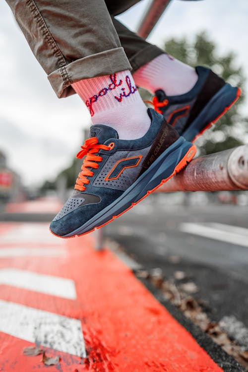Photo of a Person Wearing a Blue and Orange Shoe
