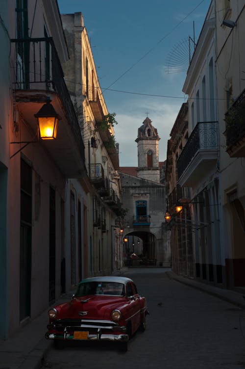 Red Vintage Car Parked on the Street Beside the Houses