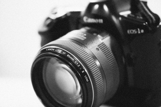 Monochrome close-up of a DSLR lens, showcasing precision detail in grayscale.