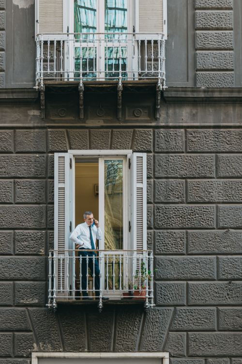 Free Adult man standing on a balcony in a historic building in Napoli, Italy. Stock Photo