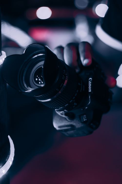 Free A close-up view of a Canon camera held by a photographer, highlighting the lens. Stock Photo