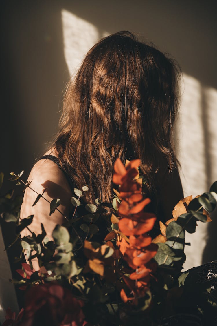 Woman With Long Brown Hair Sitting Behind Dry Bouquet Of Leaves