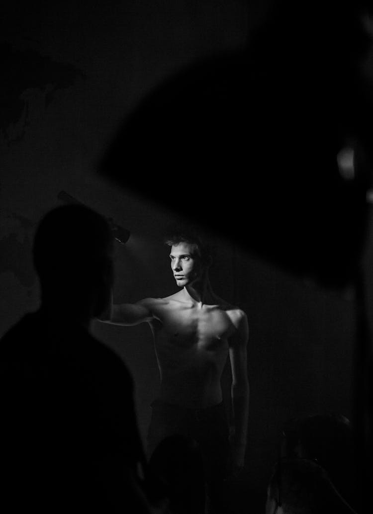 Grayscale Photograph Of A Shirtless Man Holding A Flashlight