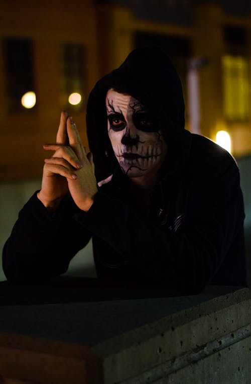A Man with Creepy Face Paint Wearing Black Hoodie while Looking Afar