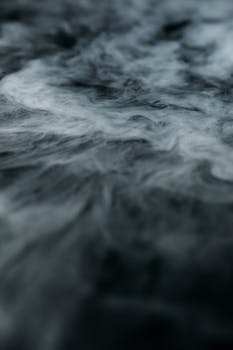 Mysterious swirling smoke forming abstract patterns on a dark surface.