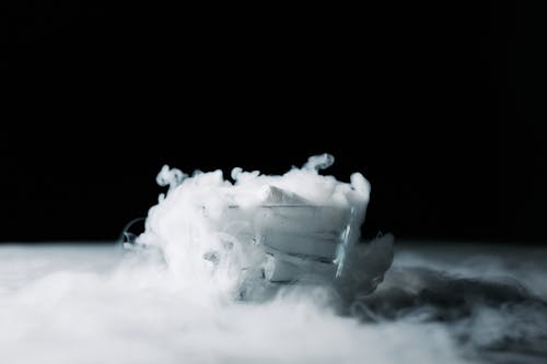 White Smoke in a Glass Container Against Black Background