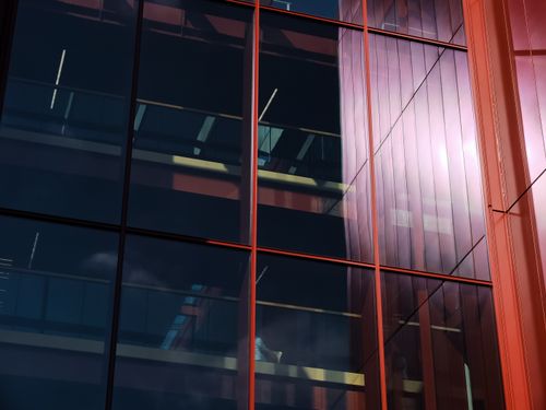 Free Close-up view of a modern glass facade reflecting sunlight with urban architectural details. Stock Photo