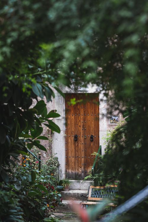 Free A rustic wooden door surrounded by lush greenery in a garden in Valldemossa, Spain. Stock Photo