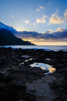 一片令人惊叹的沿海景观，多岩石的海岸与充满活力的日落交相辉映