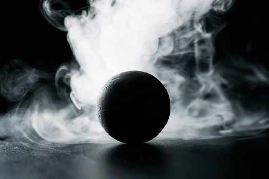 A dark sphere surrounded by swirling smoke creates a mysterious and dramatic scene.